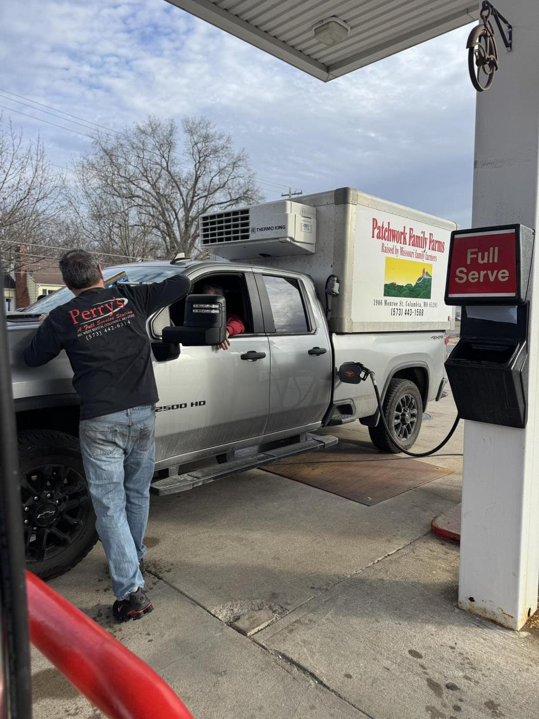 An attendant in a Perry's shirt filling a customer's pickup at the pump, with the Full Serve sign on the island